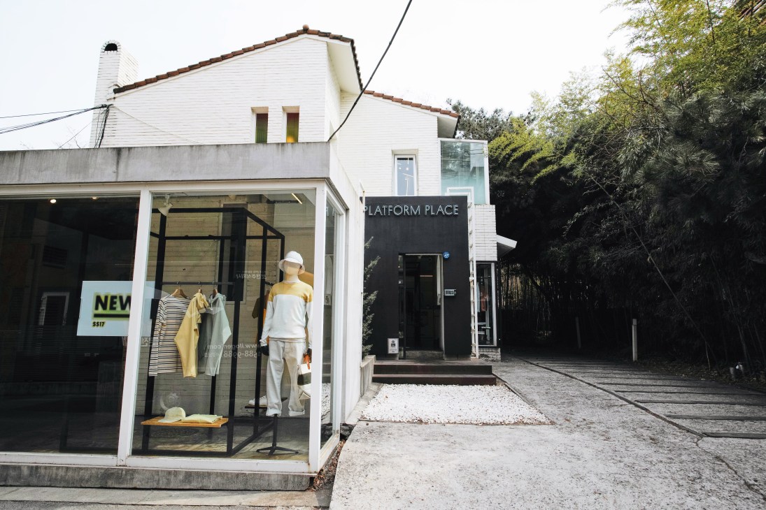 Platform Place storefront with white brick exterior, black entrance, and clothing displays in window.