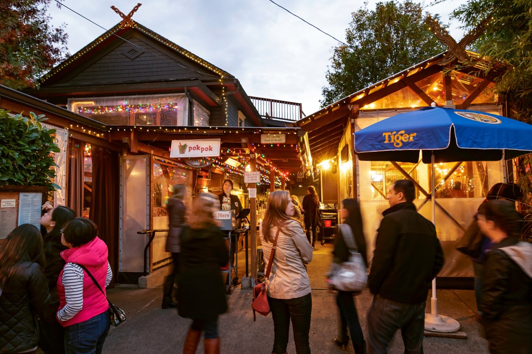 Illuminated Pok Pok restaurant storefront at night with crowds of people outside, Portland.