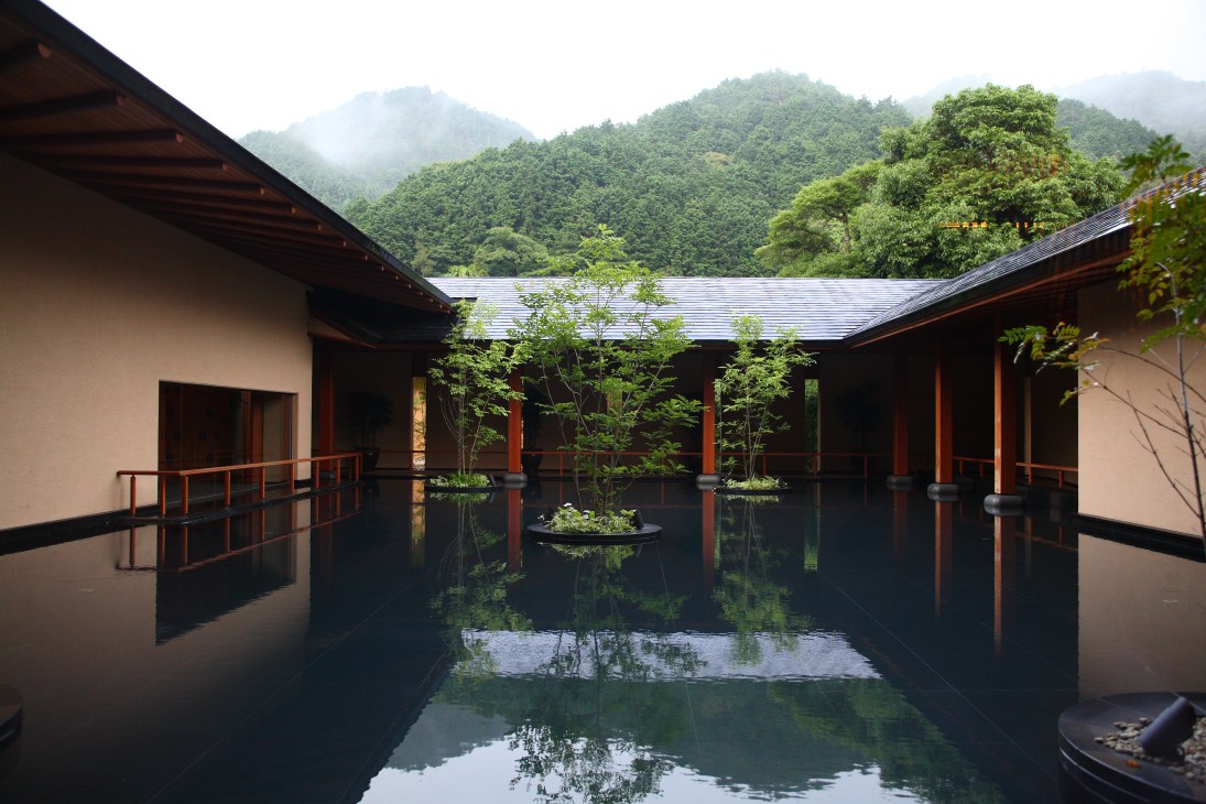 Bettei Otozure ryokan courtyard with reflecting pool, wooden railings and mountain views.
