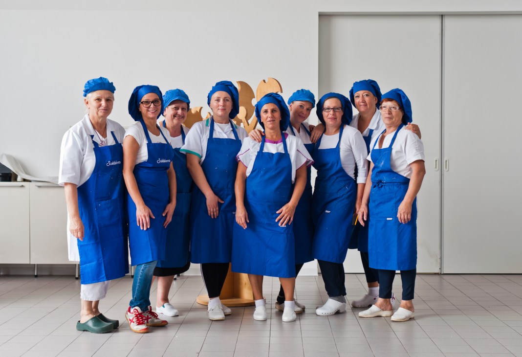 The Scaldaferro nougat factory team in blue aprons and hairnets posed in their white factory.