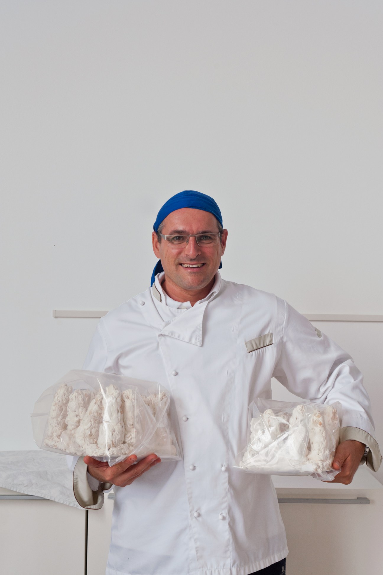 Pietro Scaldaferro, production manager, holding fresh nougat in white chef's coat and blue headband.
