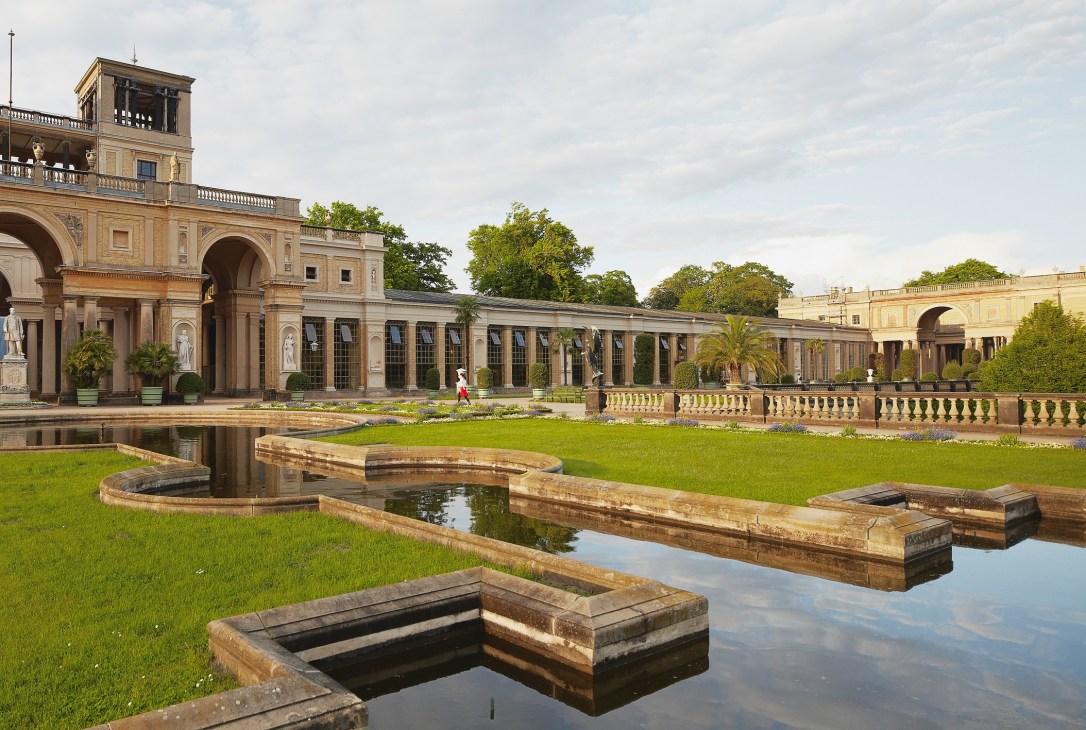Ornate 18th-century palace building with neoclassical architecture, manicured gardens, and stone water channels at Potsdam.