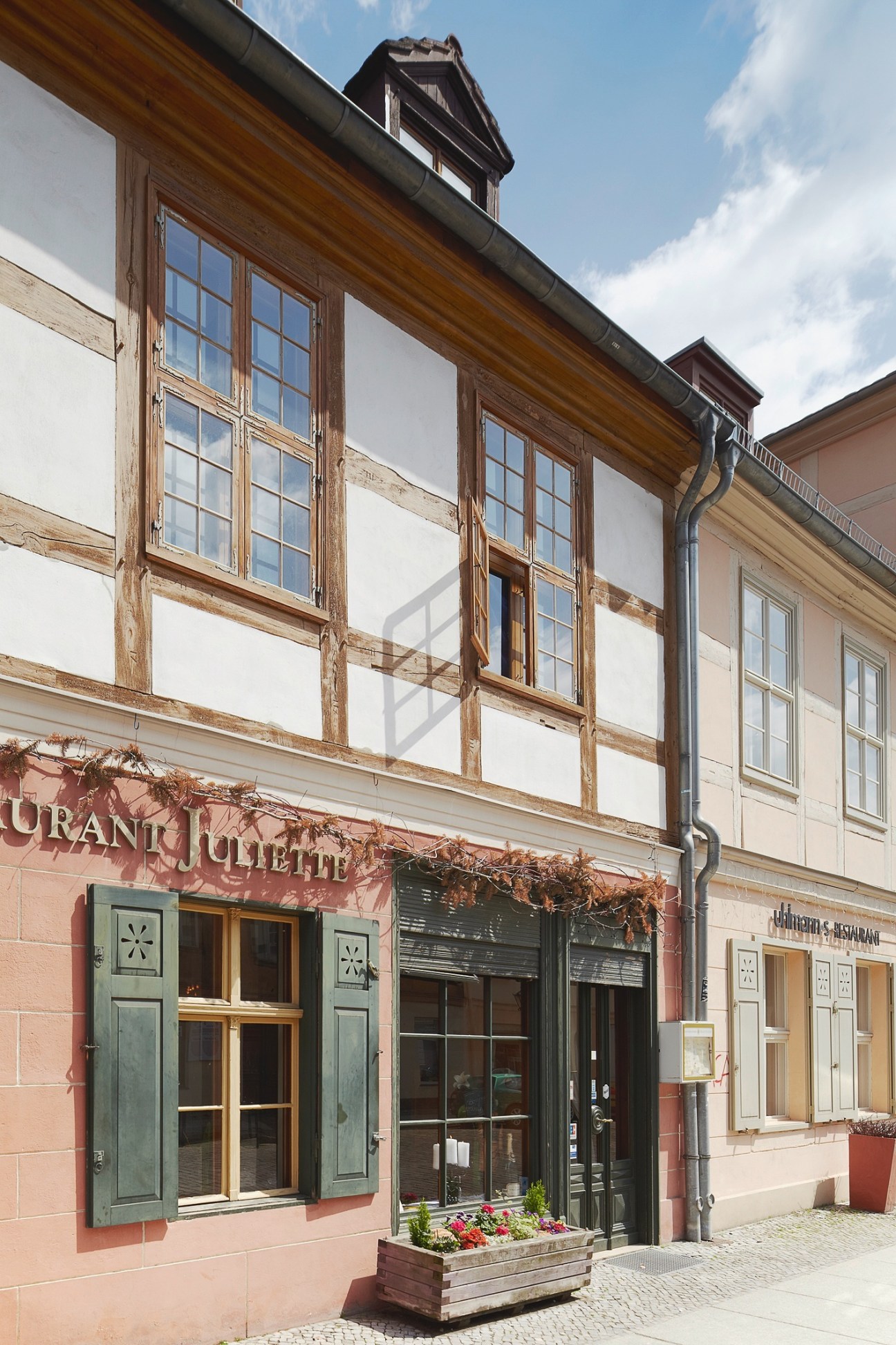 Half-timbered building with pink ground floor and green shutters in Potsdam.