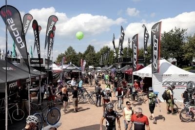 Outdoor testing area at Eurobike trade fair with vendor booths, bicycles, and visitors on a sunny day.