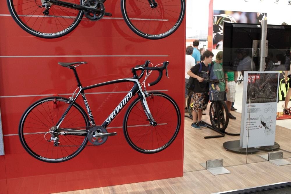 Specialized 2012 Tarmac road bikes displayed on a red wall at Eurobike trade show.