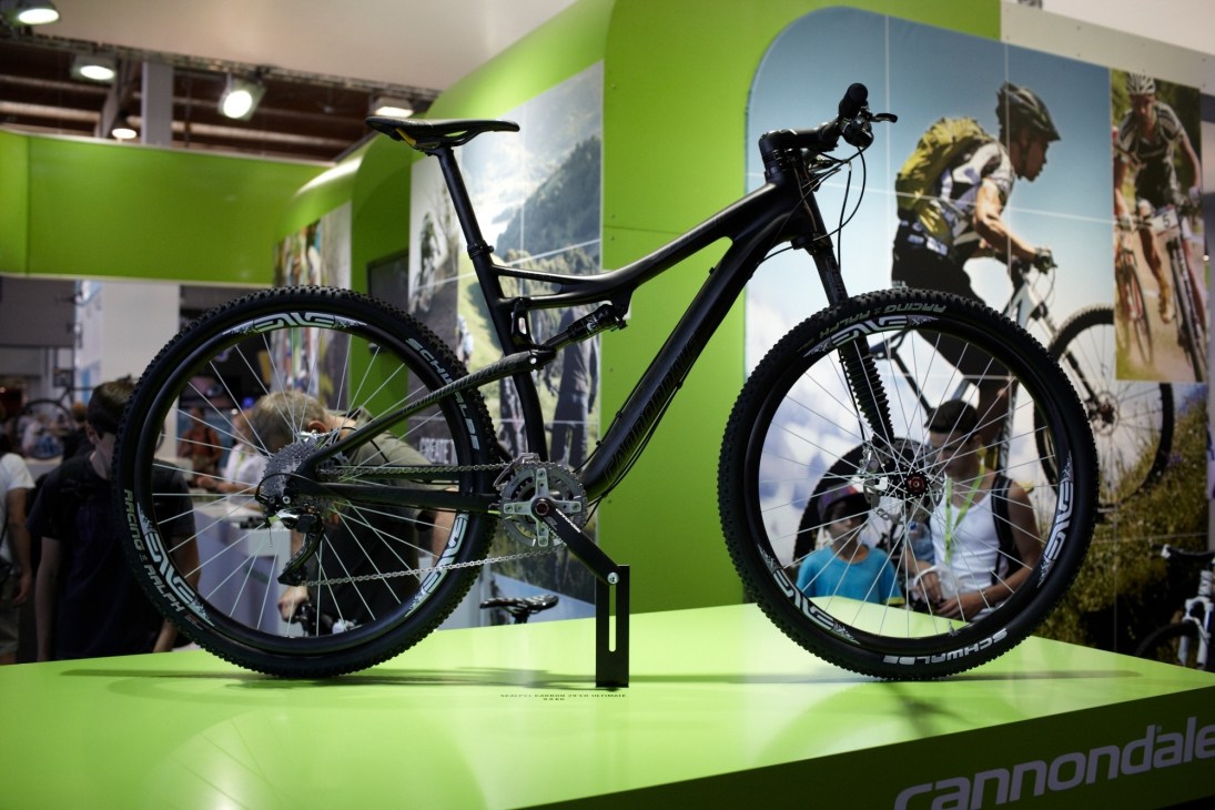 Black Cannondale Scalpel Ultimate 29er mountain bike displayed on bright green platform at trade show.