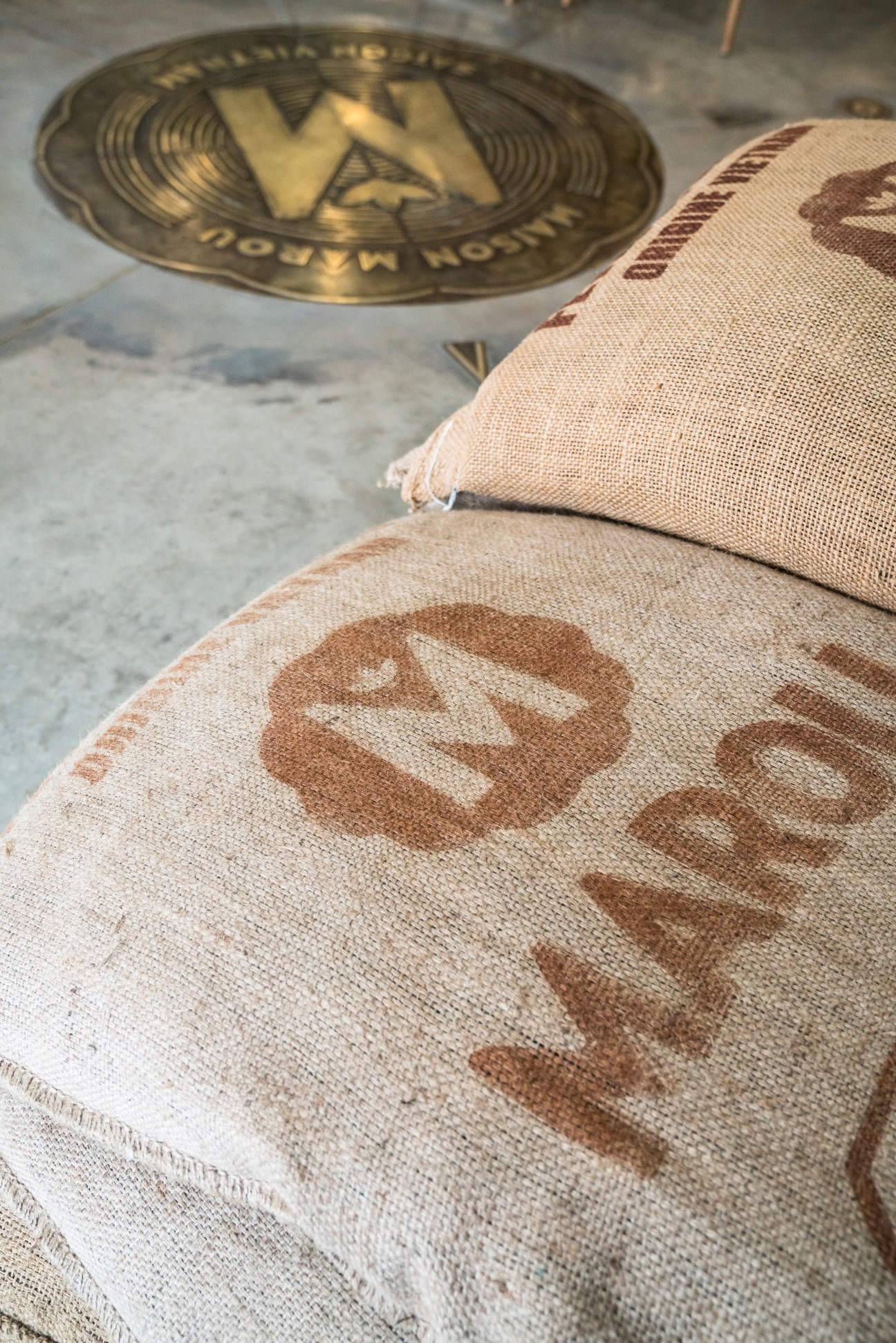 Marou-branded burlap sacks of raw cacao beans next to the brand's logo.