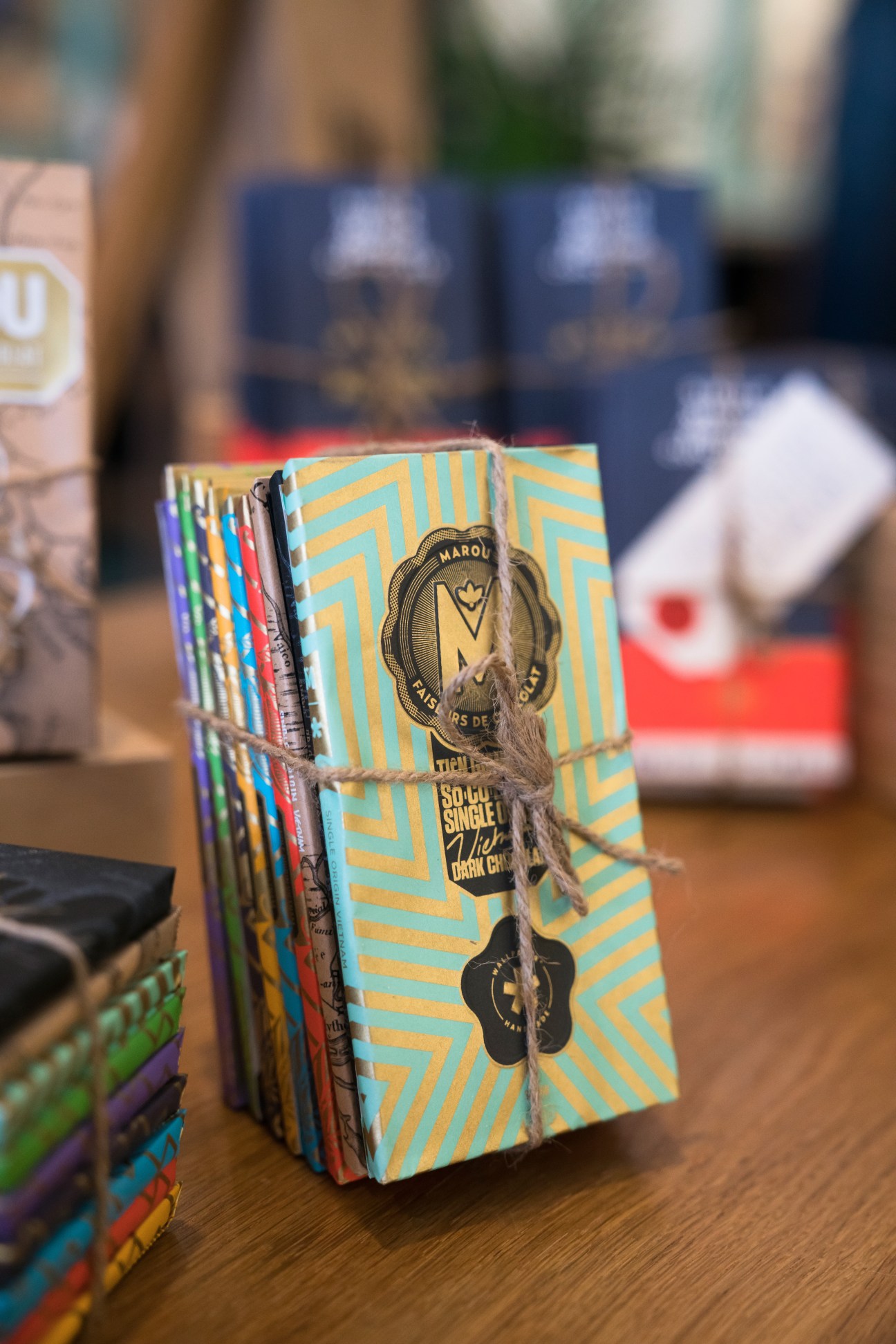 Marou chocolate bars with colorful geometric packaging stacked and tied with twine at the shop.
