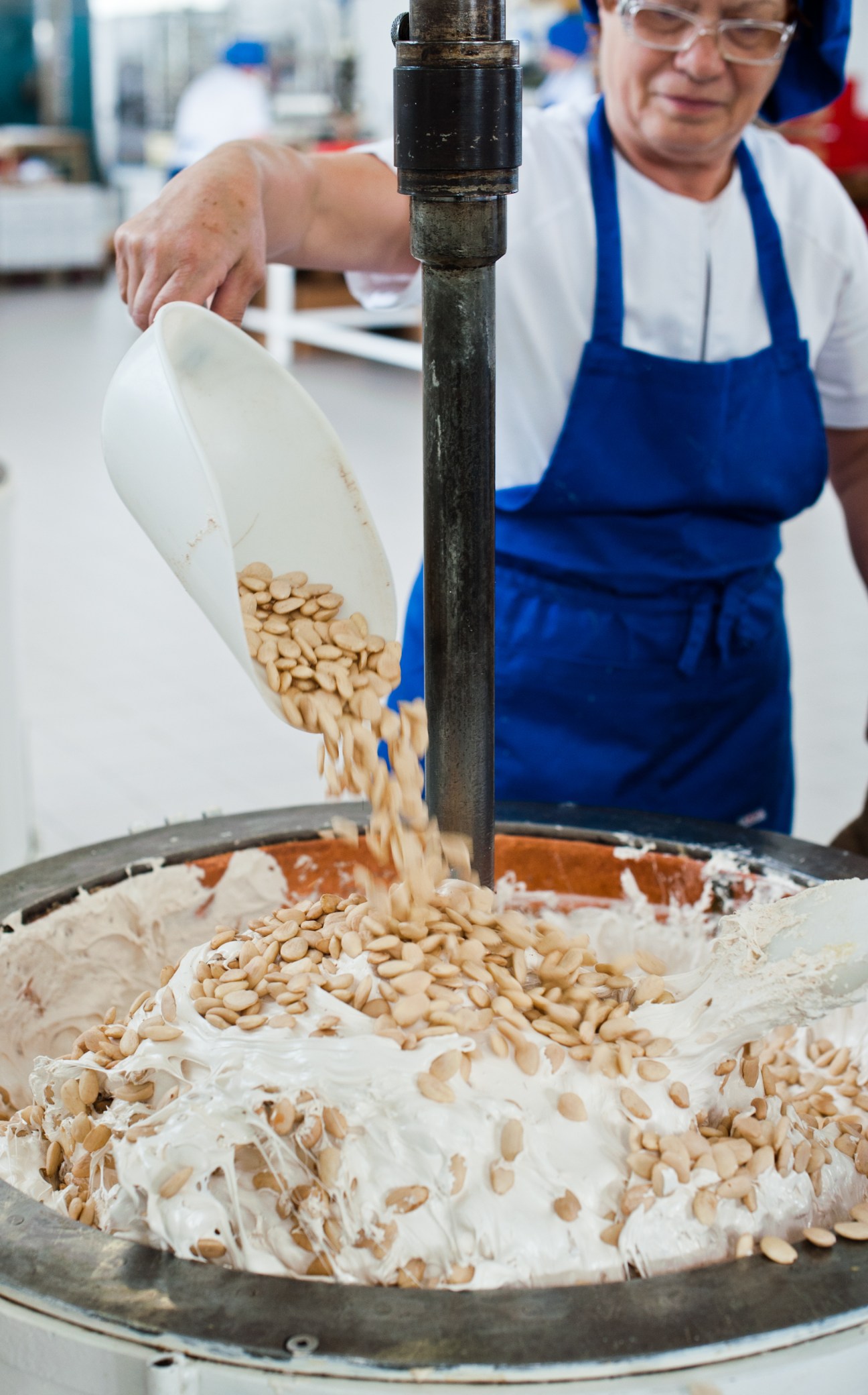 A Scaldaferro worker pouring toasted almonds into nougat mixture during production.