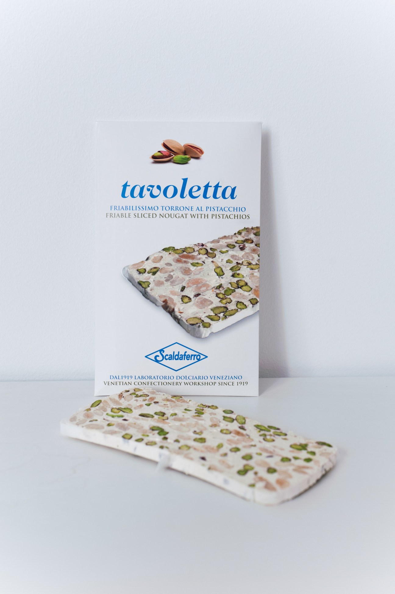 Scaldaferro tavoletta pistachio nougat package and sliced pieces with visible pistachio nuts.