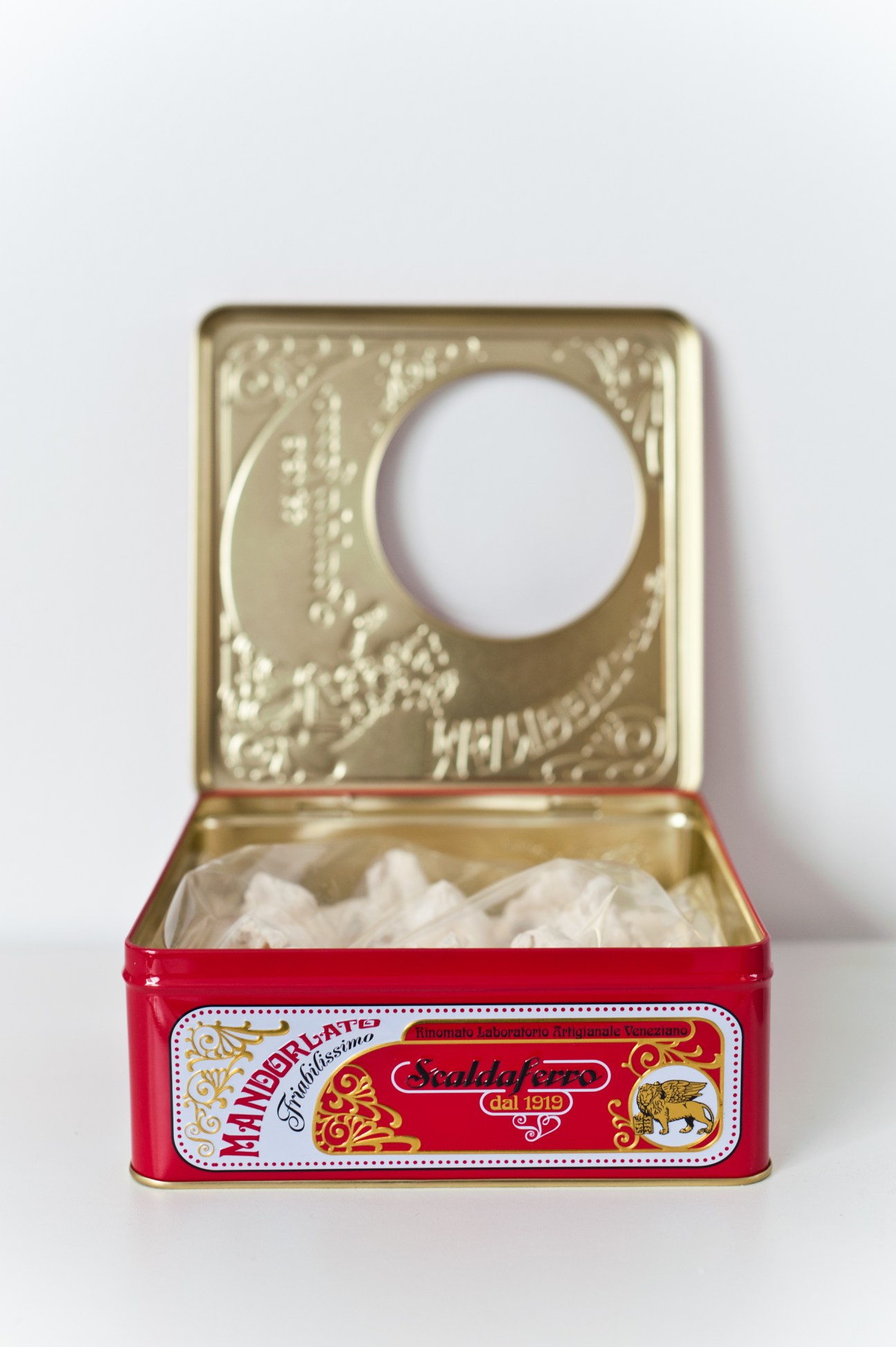 Open red Scaldaferro nougat tin with gold interior and white wrapped nougat inside