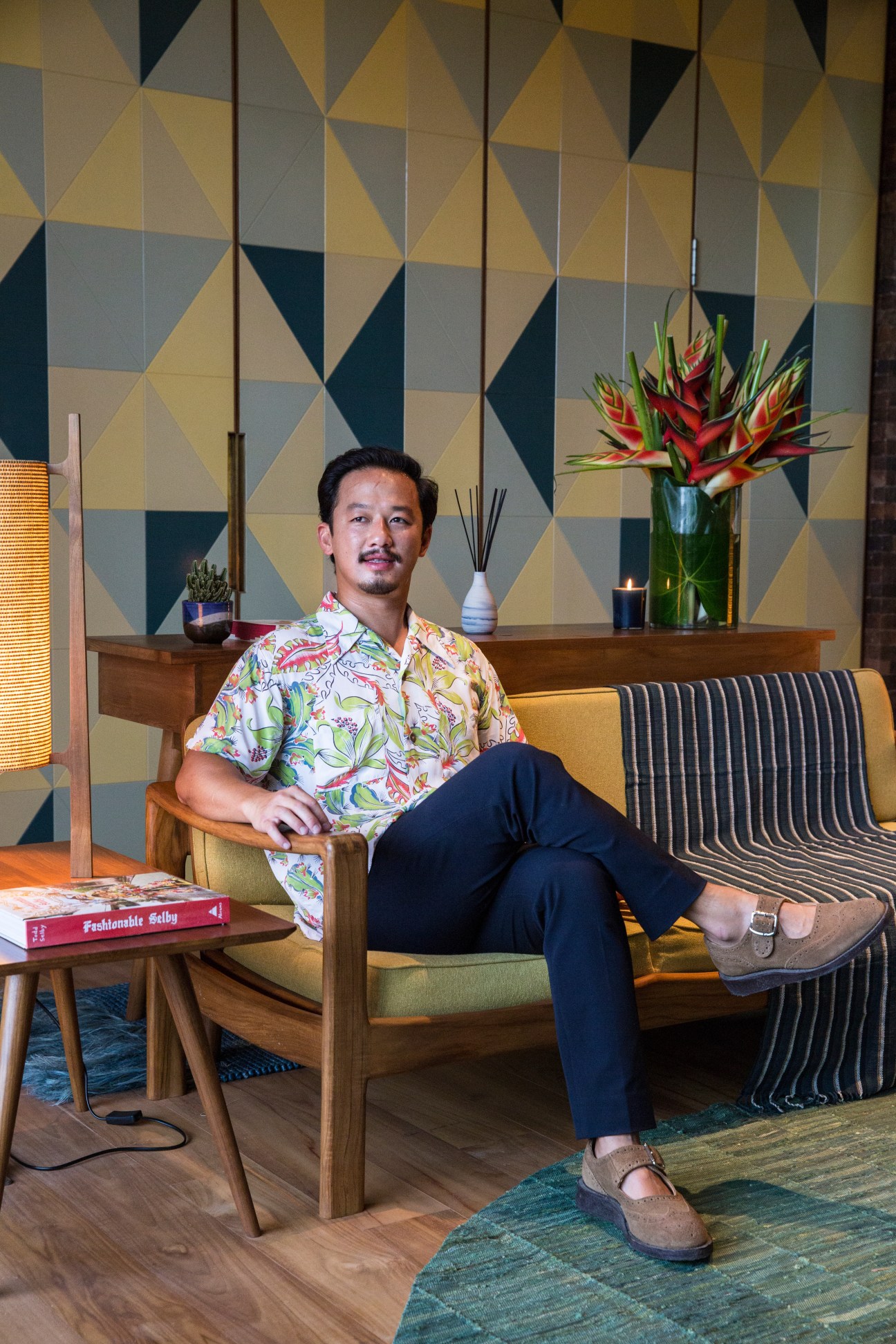 Ronald Akili, co-founder of PTT Family, seated in a mid-century modern lounge chair in the Katamama hotel lobby.