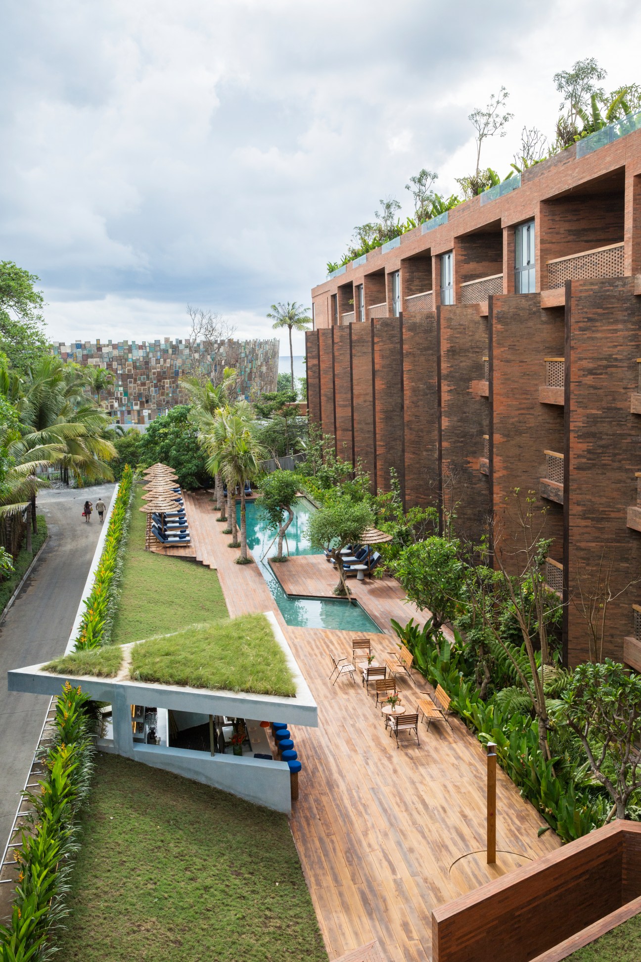Aerial view of Katamama hotel's brick building, courtyard with pool, and lush tropical landscaping in Bali.