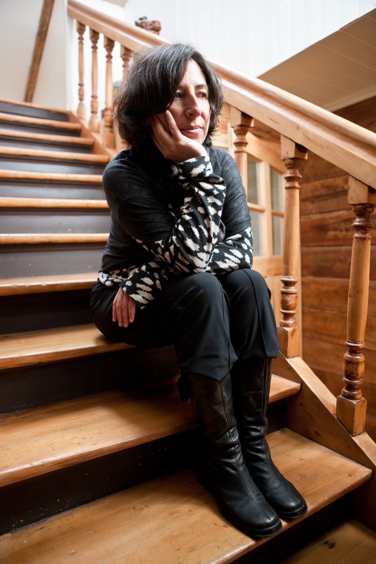 Interior design consultant Teresa Varas sitting on wooden stairs in her restored home in Puerto Varas.