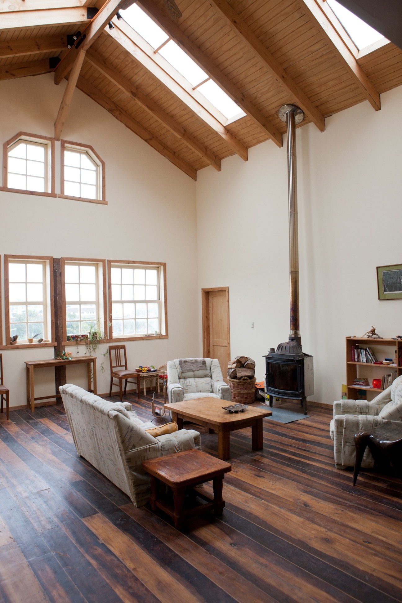Spacious living room with wooden beams, large windows, fireplace and rustic furnishings in Vicki Johnson's converted warehouse.