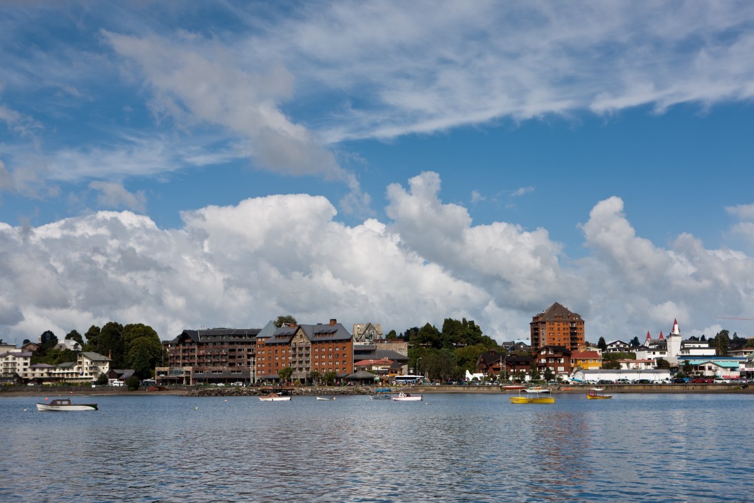 Puerto Varas waterfront with colorful buildings, boats on Lake Llanquihue, and cloudy sky.