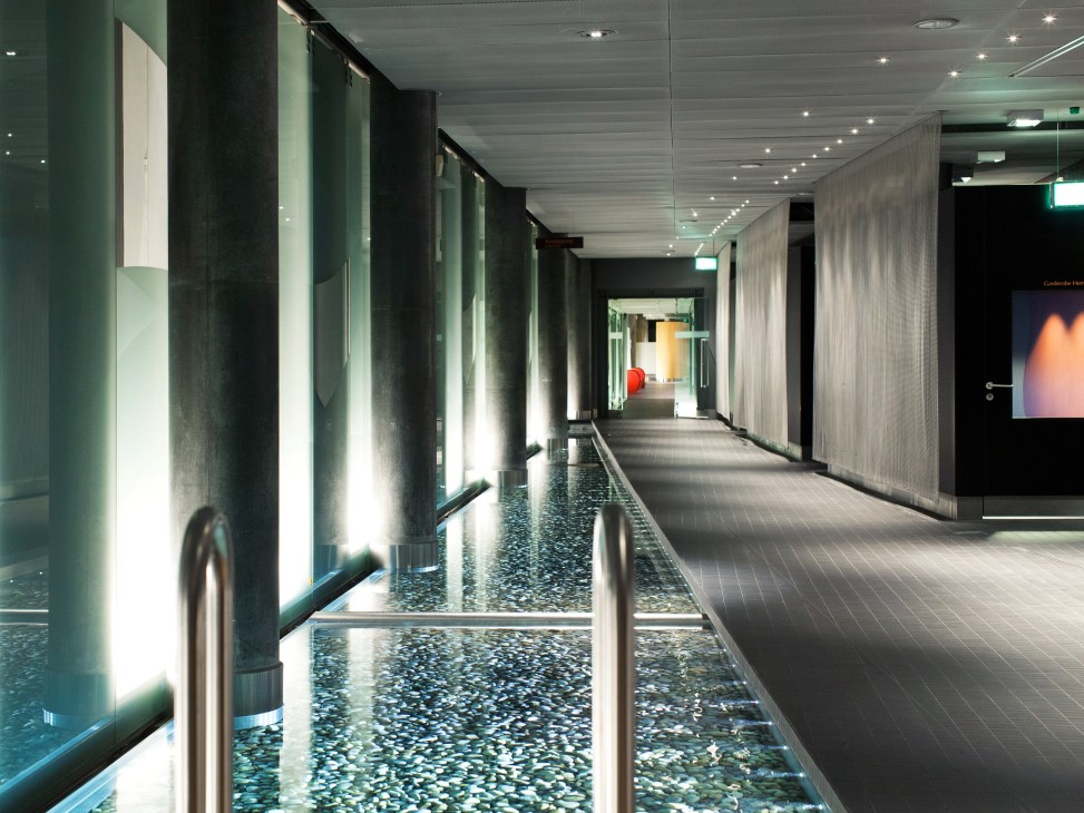 Modern corridor with illuminated columns and polished terrazzo floor at Puls 5's Kneipp walk.