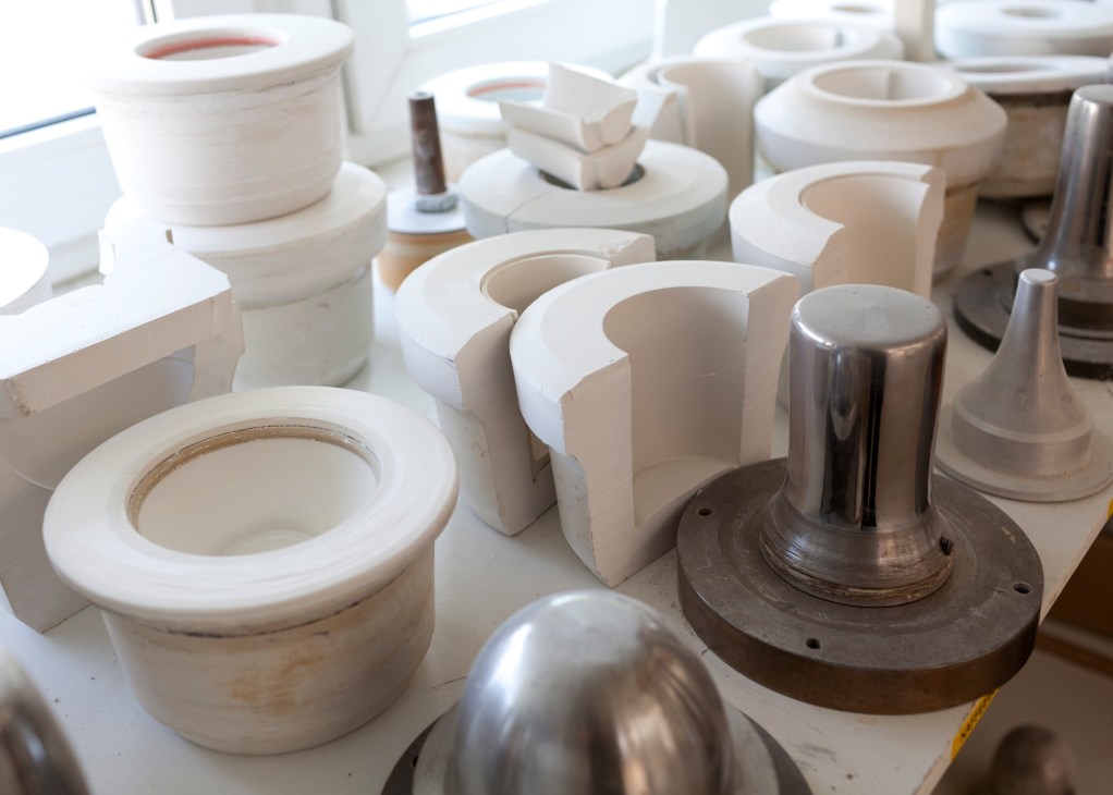 White porcelain forms and metal molds arranged on a surface during production.