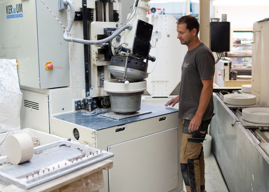 A factory worker operates a porcelain manufacturing machine in the Hering Berlin production facility.
