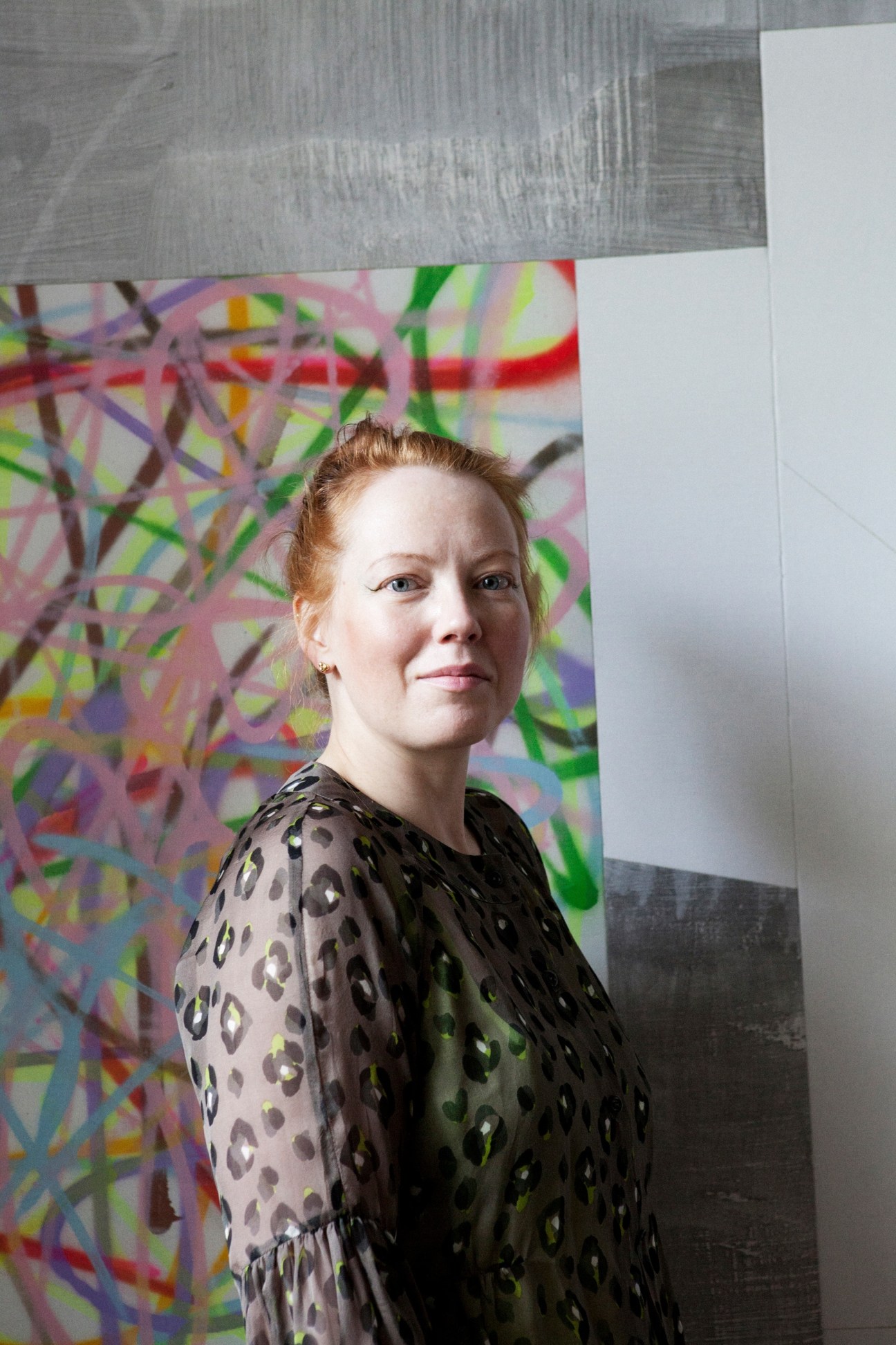 Julia Muggenburg, collector and jewellery designer, poses in front of colorful abstract artwork in her London home.
