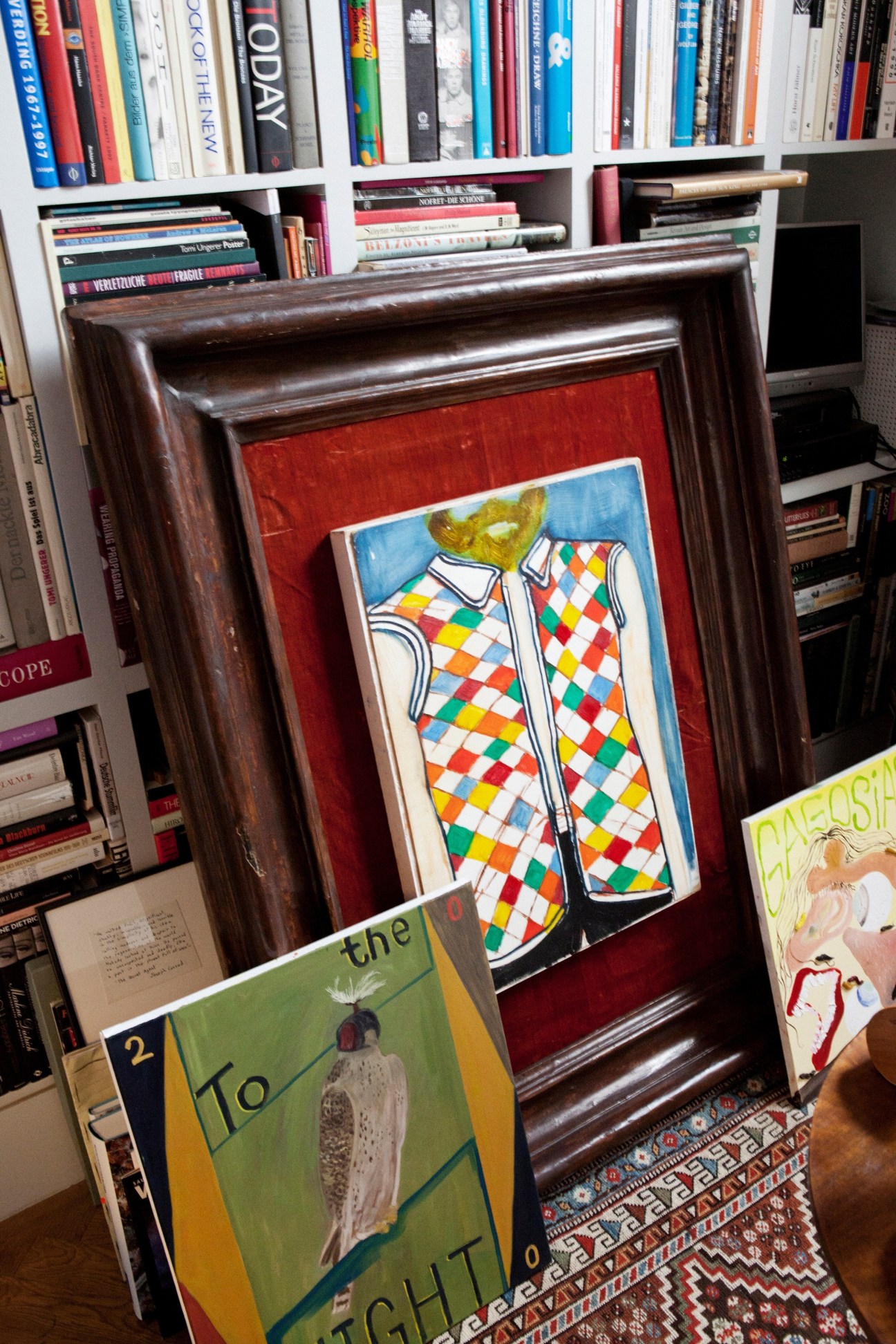 Colorful framed artwork with geometric argyle pattern displayed against bookshelves in Julia Muggenburg's collection.