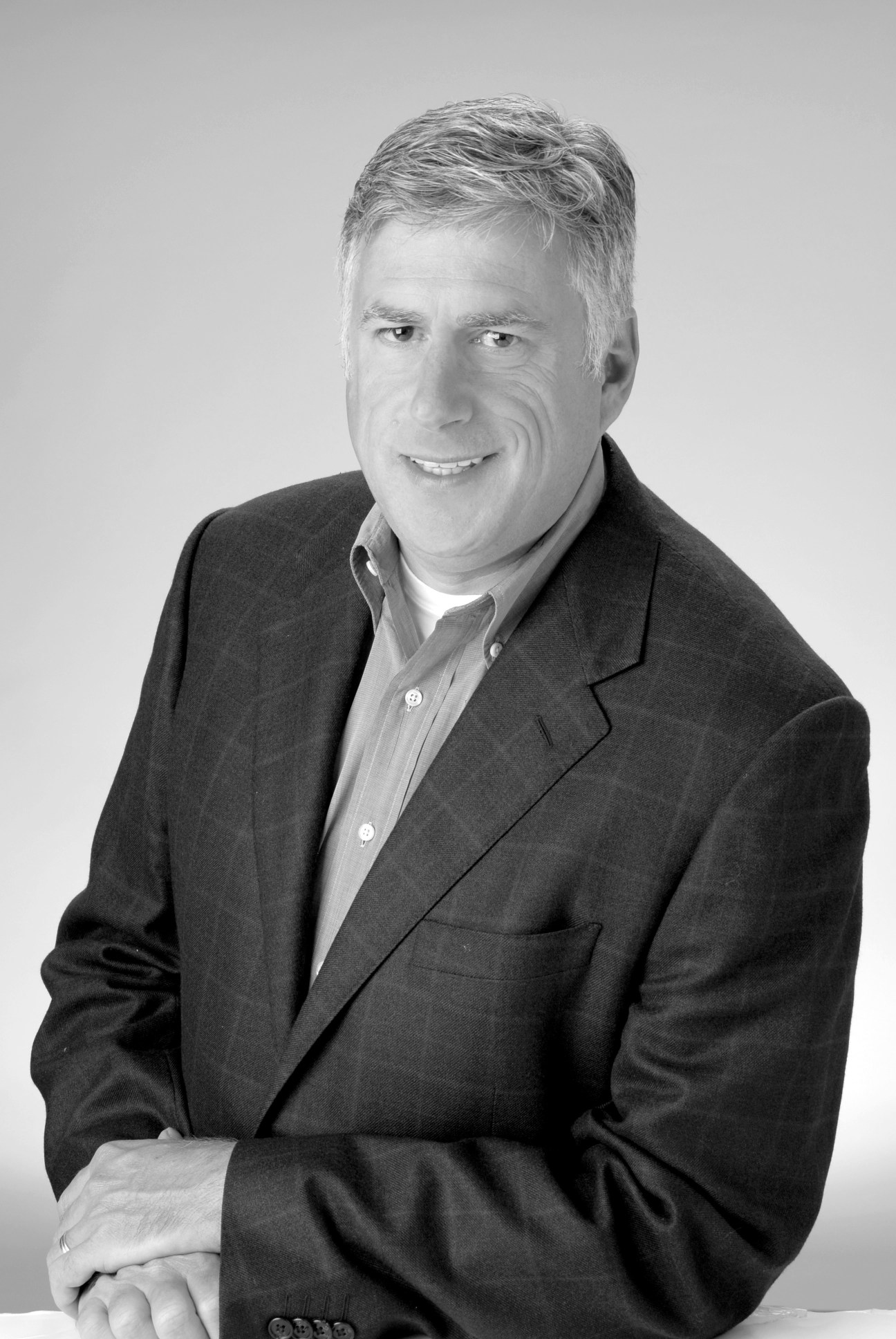 Black and white portrait of Keith Granet, a man in a dark blazer and light shirt, smiling at the camera.