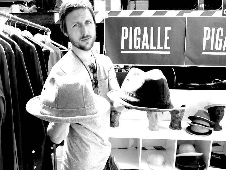 Hugo Bergström, creative director of Nitty Gritty, posing with fedora hats at a display stand.