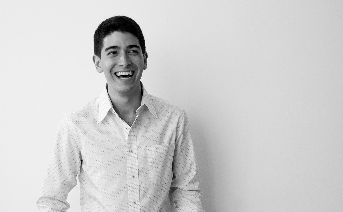 Portrait of Steve Daniels, editor of Makeshift magazine, smiling at the camera wearing a white button-up shirt.