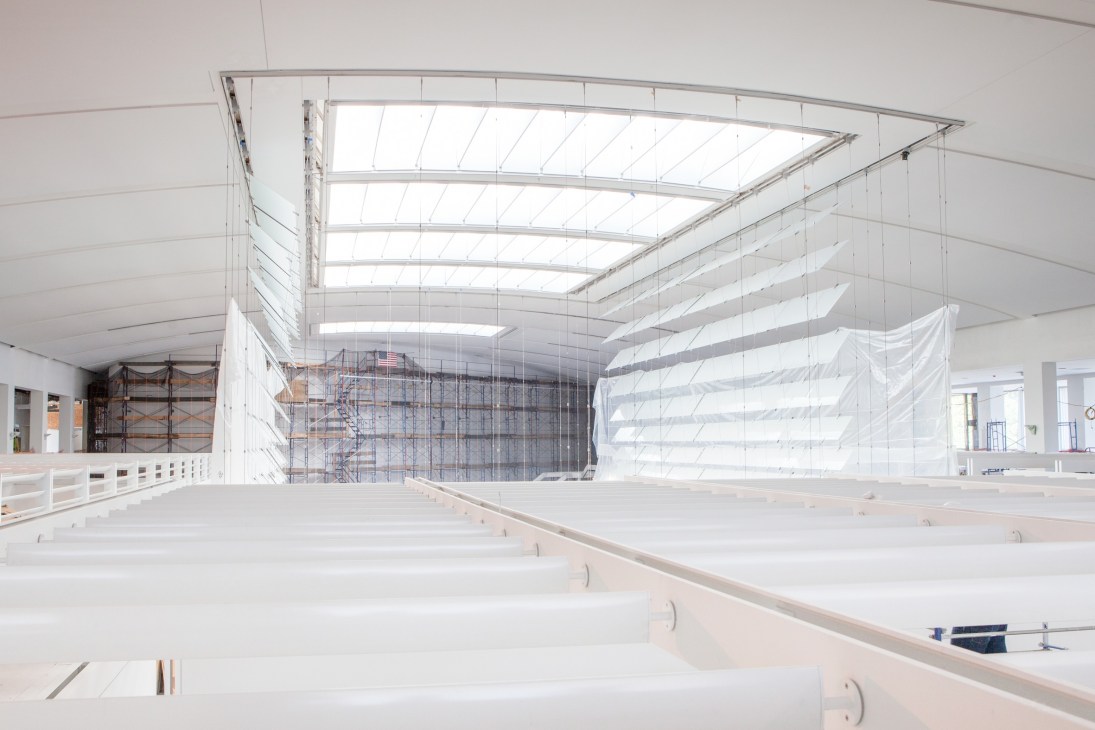 Bright modern atrium with skylights and hanging glass structure sheets in renovated Queens Museum of Art.