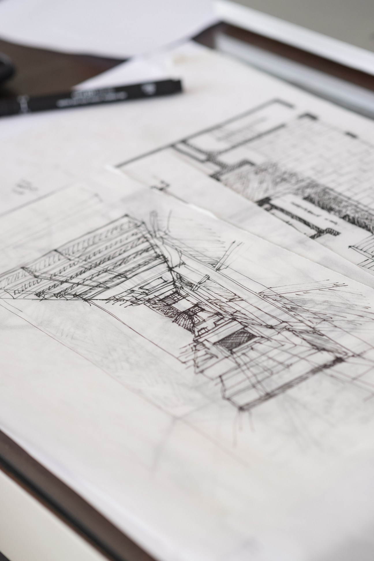 Architectural sketches and drawings on white paper with a pen on a desk.