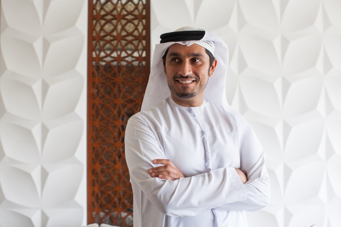 Mohammad Al-Shehhi, COO of D3, stands smiling with arms crossed in front of textured wall panels.