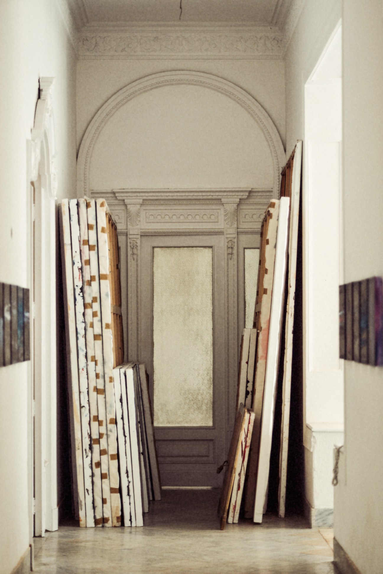 Narrow upstairs corridor in Rachel Valdés Camejo's art deco villa studio displaying rolled canvas and fabric samples leaning against cream walls.