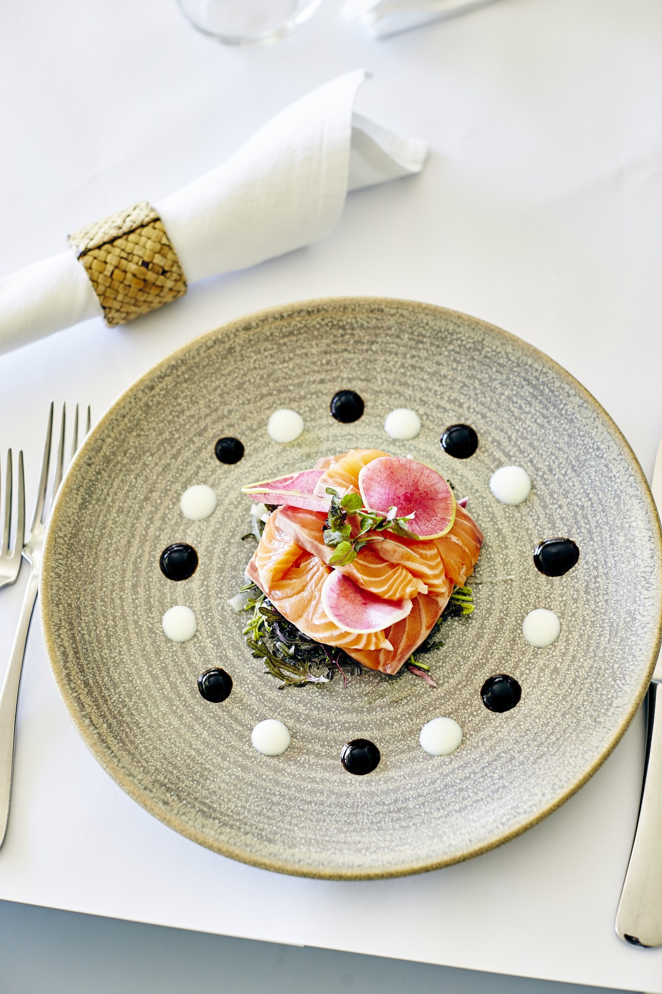 Plated salmon dish with radish slices, microgreens, and black and white dots at fine dining restaurant Rae's.