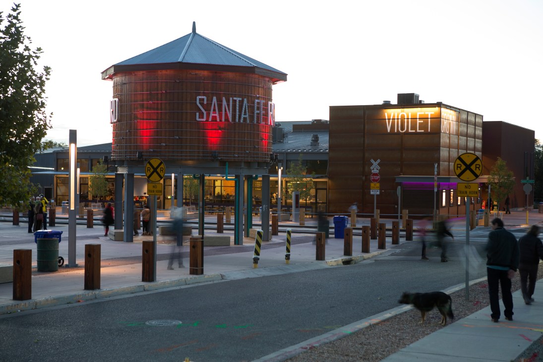 Violet Crown Cinema building with red water tower and neon signage in Santa Fe's Railyard at dusk.