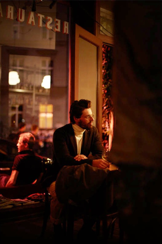 Model Nikolaij Schulz seated in a Berlin bar wearing Bottega Veneta jacket and The North Face coat.
