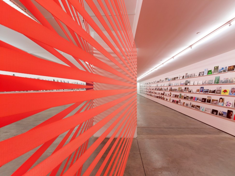 Interior of Rampa Gallery in Istanbul showing red geometric wall installation and white shelving with artworks.