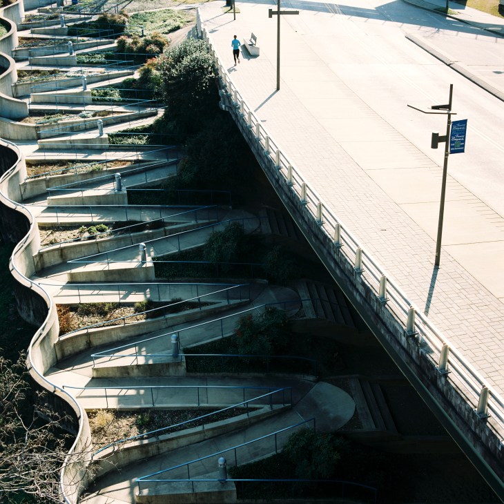 Tiered concrete steps descend toward the Tennessee River with vegetation growing between levels and a pedestrian plaza visible above.