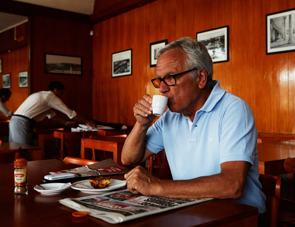 Reinaldo Tomaz, a Cascais native, drinks espresso at a café with wood-paneled walls.