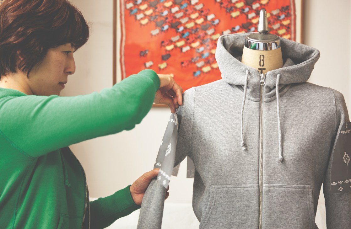 Pattern designer Fumiko Ishimoto adjusts a gray zip-up hoodie on a dress form.