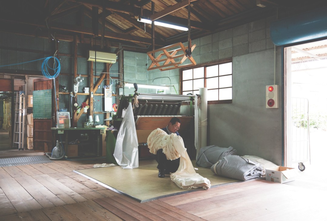 A worker manually turns newly knitted cloth right-side out in a Wakayama textile factory.