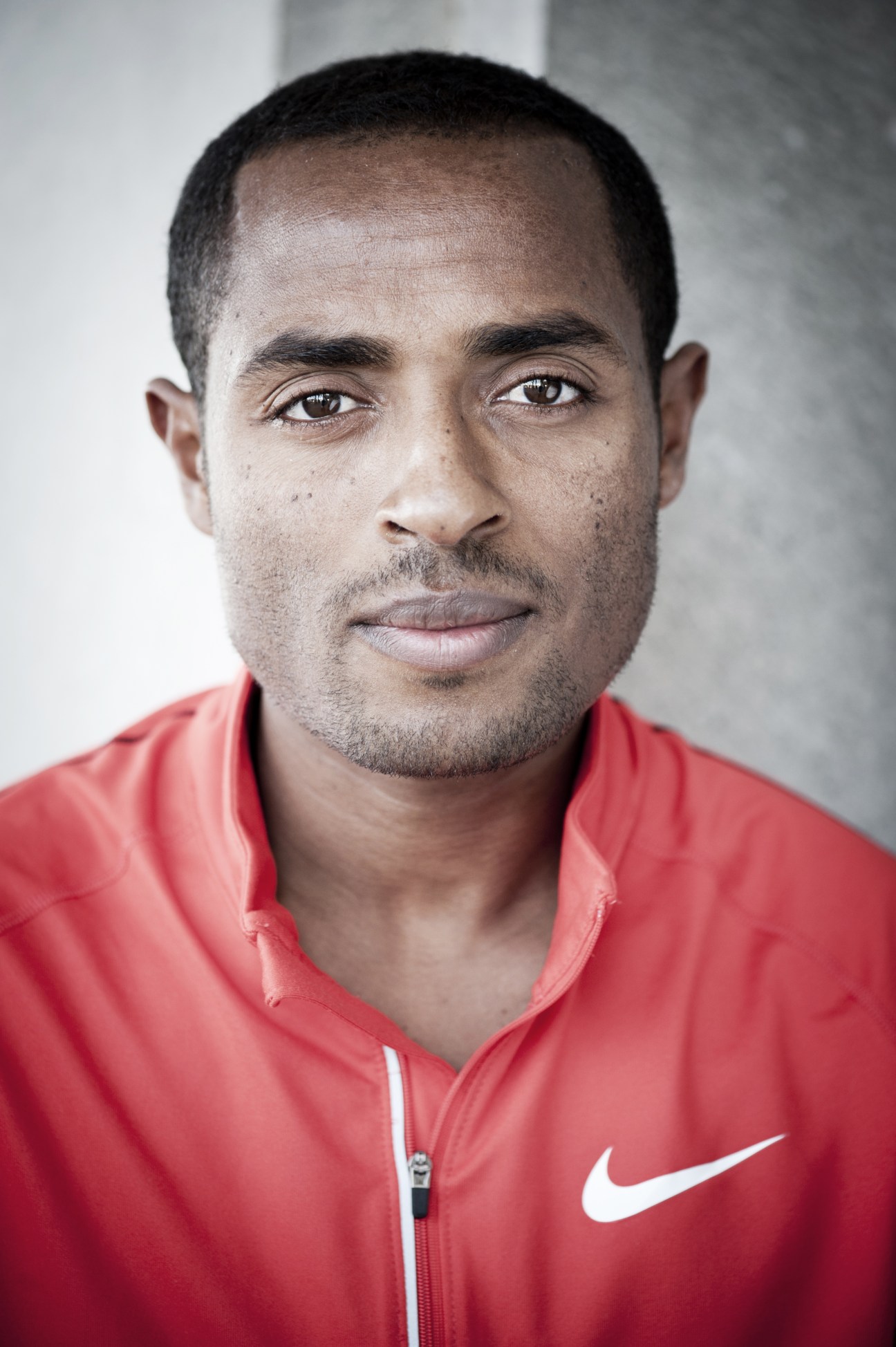 Portrait of Kenenisa Bekele, Ethiopian Olympic distance runner, wearing a red Nike jacket.