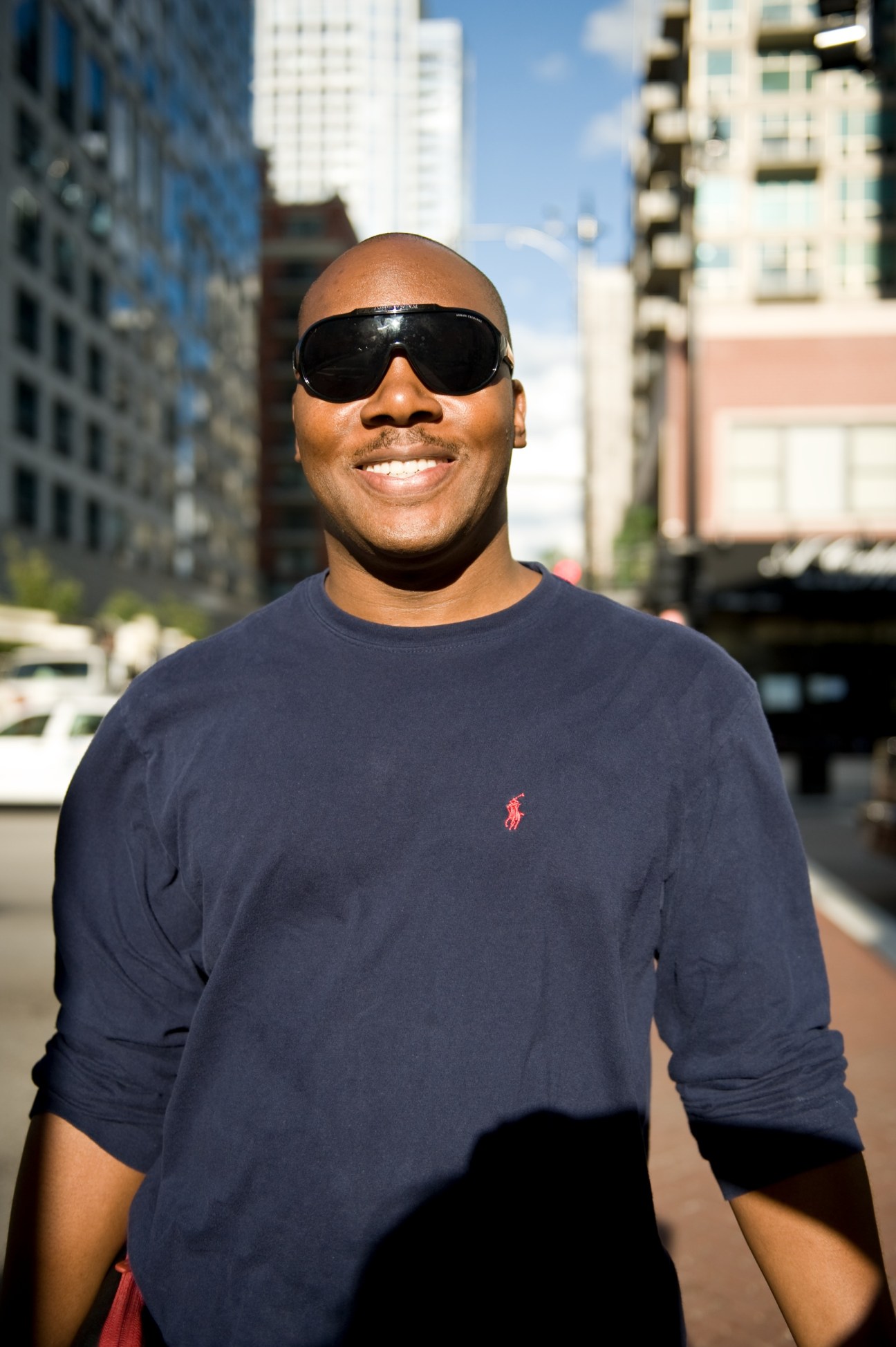 Lanre Sarumi, a filmmaker and South Loop resident, smiling on a city street with buildings behind him.