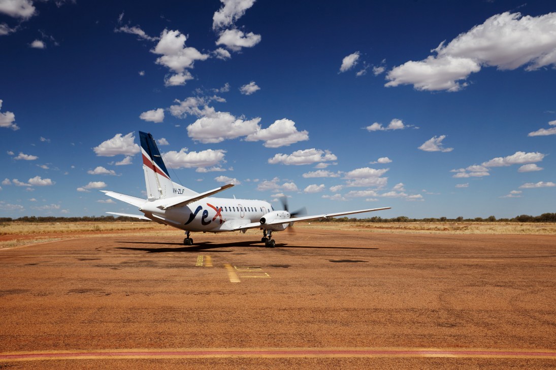 Regional Express Saab 340 aircraft parked on a red dirt runway in outback Queensland.