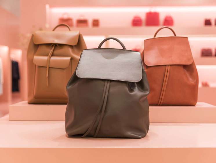 Mansur Gavriel men's calf-leather backpacks displayed on pink shelves in the brand's Soho store.