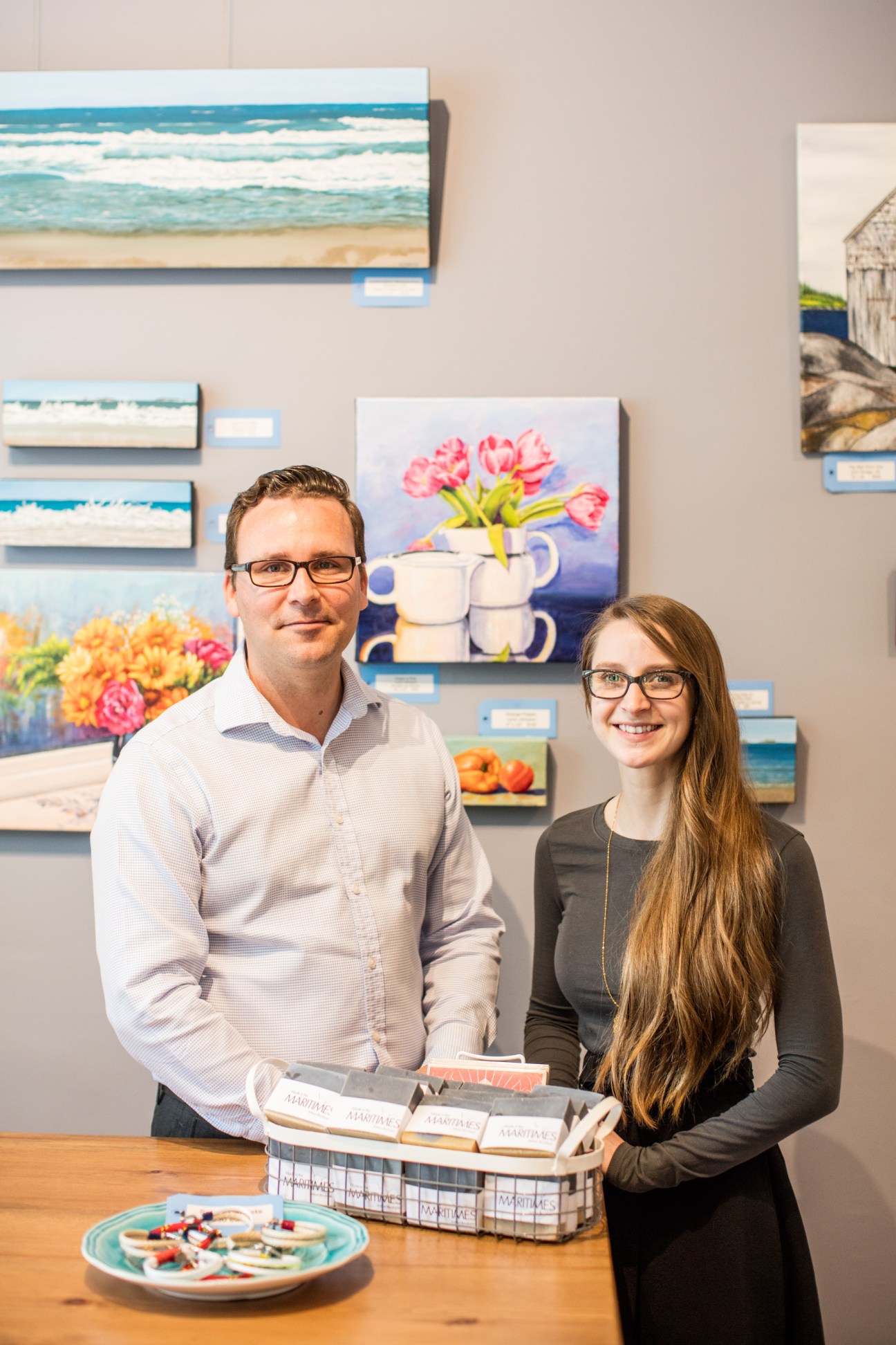 Two people standing in an art gallery with paintings on the wall behind them