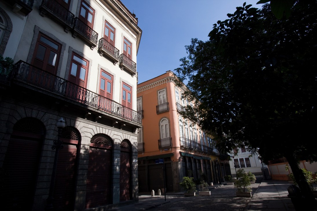 Colonial-era buildings with white and terracotta facades line a sunny street in Rio de Janeiro's Centro district.