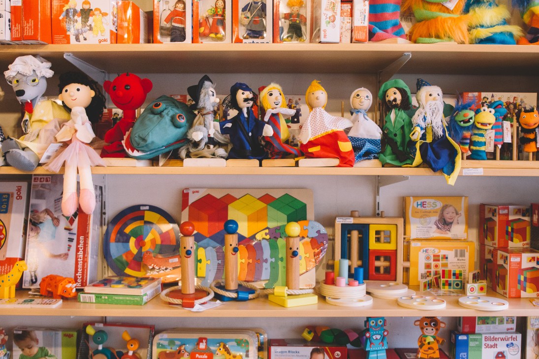 Shelves displaying colorful toys, puppets, and board games at Ristanc toy shop in Ljubljana.