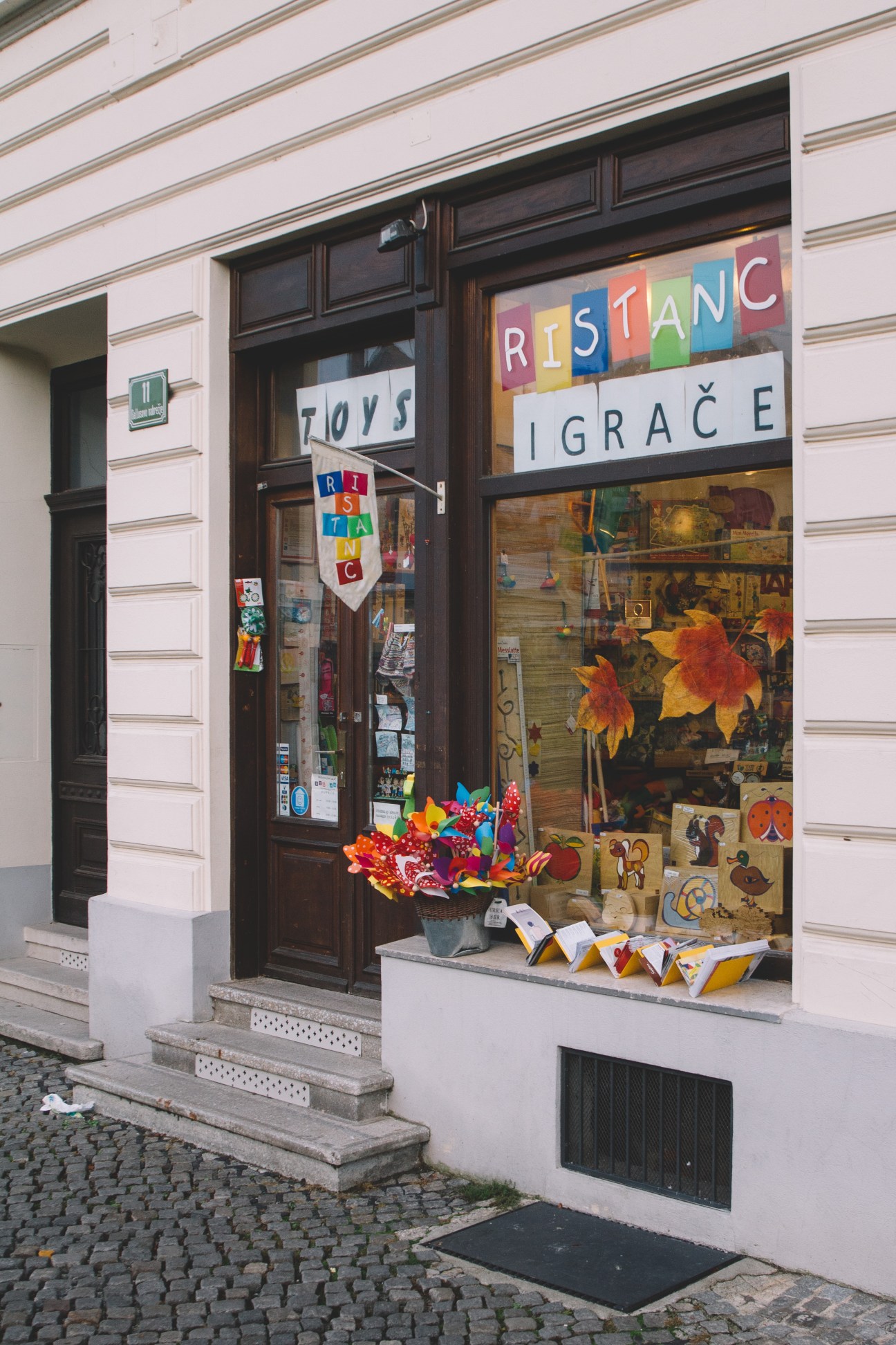Storefront of Ristanc toy shop with colorful sign and autumn decorations in window display.