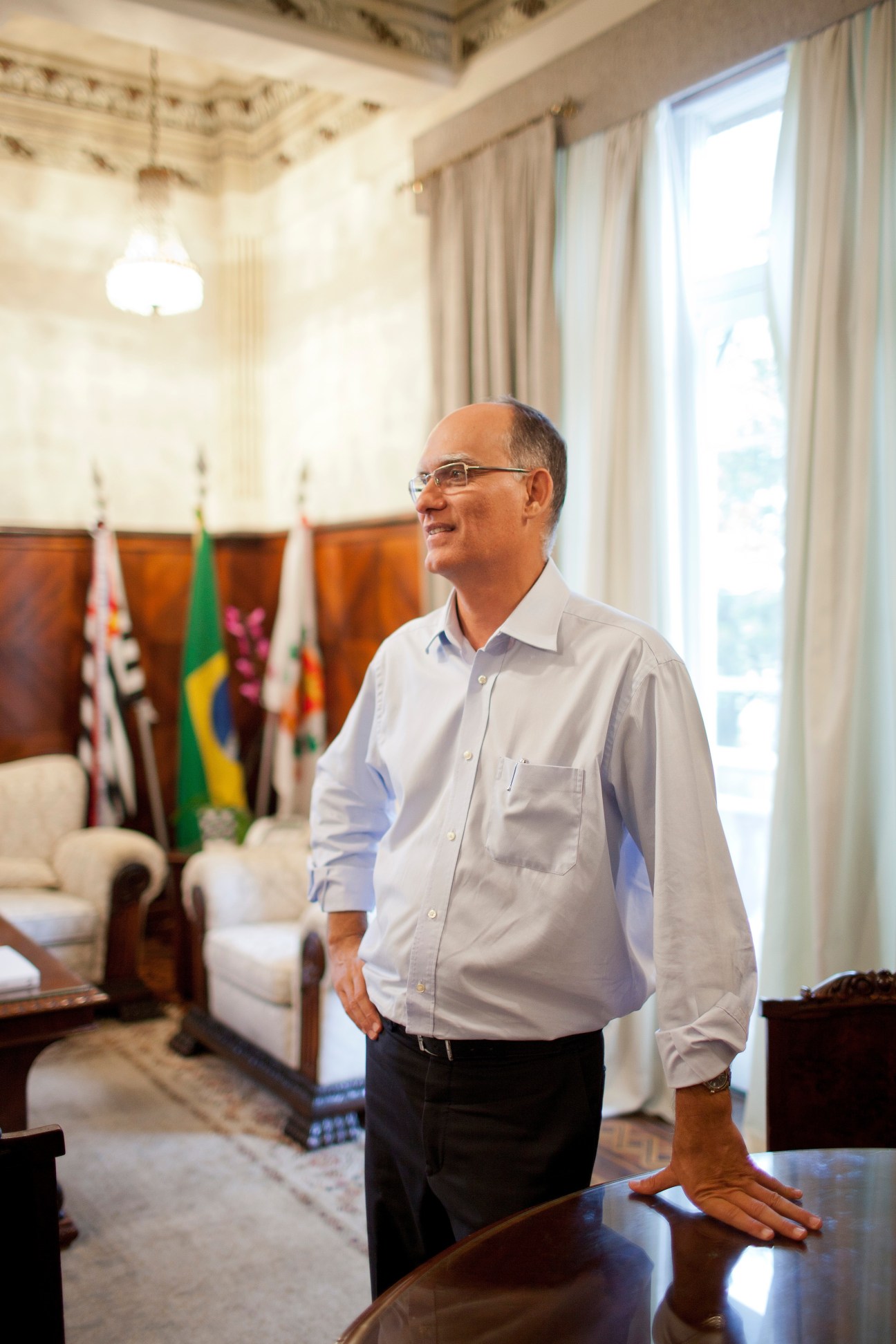 Mayor João Paulo Tavares Papa stands in an elegant interior with flags and formal furnishings.