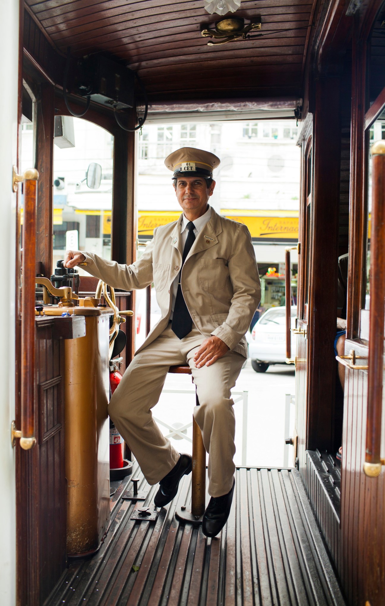 Man in uniform and captain's hat standing inside a vintage electric car.